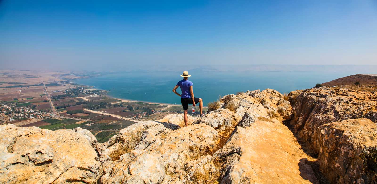A visitor in a sun hat looking out over the Sea of Galilee, Israel