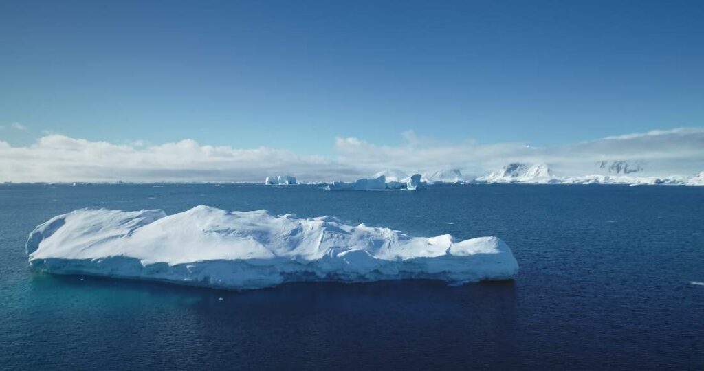 A large blue iceberg reflected in calm Antarctic water