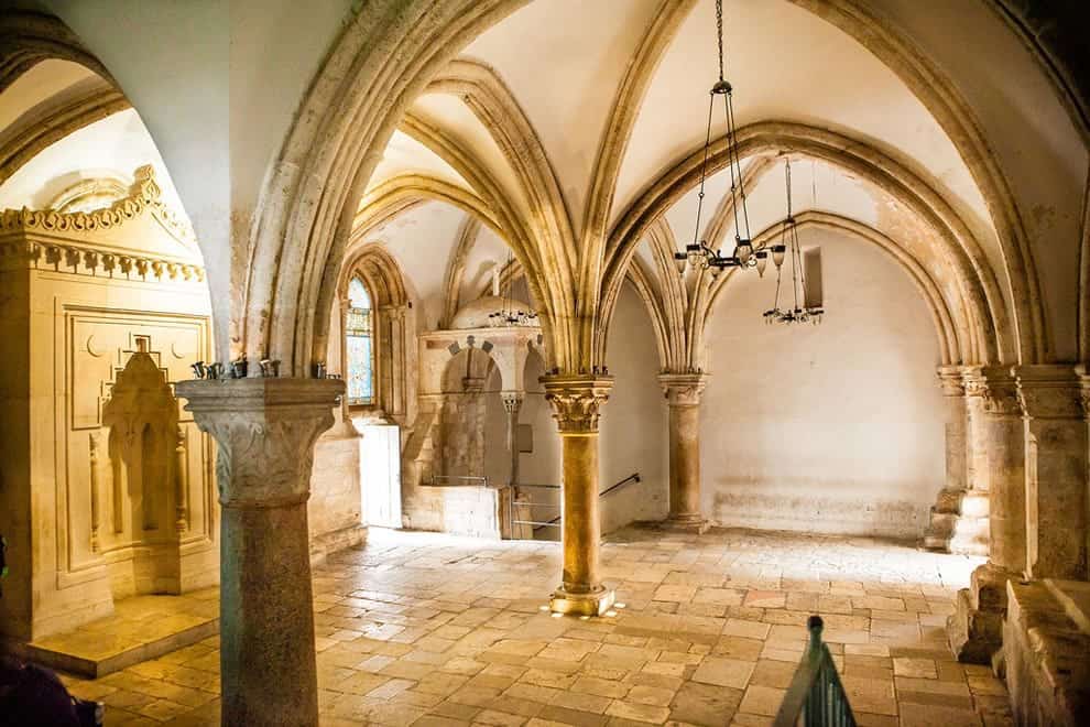 The vaulted Gothic interior of the Cenacle on Mount Zion, with ribbed arches springing from stone columns and a carved niche in the wall